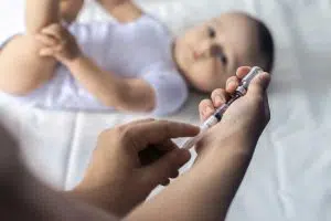 Photo of someone drawing a vaccine with a baby in the background