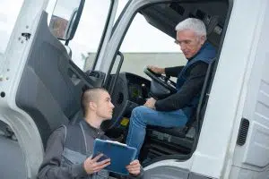 photo of 2 men talking by a semi truck