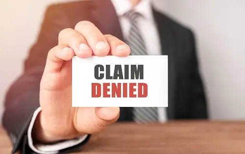 Man holding insurance claim denied card