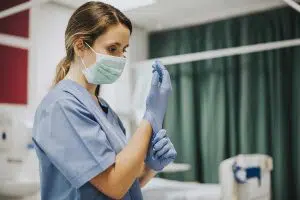 photo of a nurse putting glove and PPE on