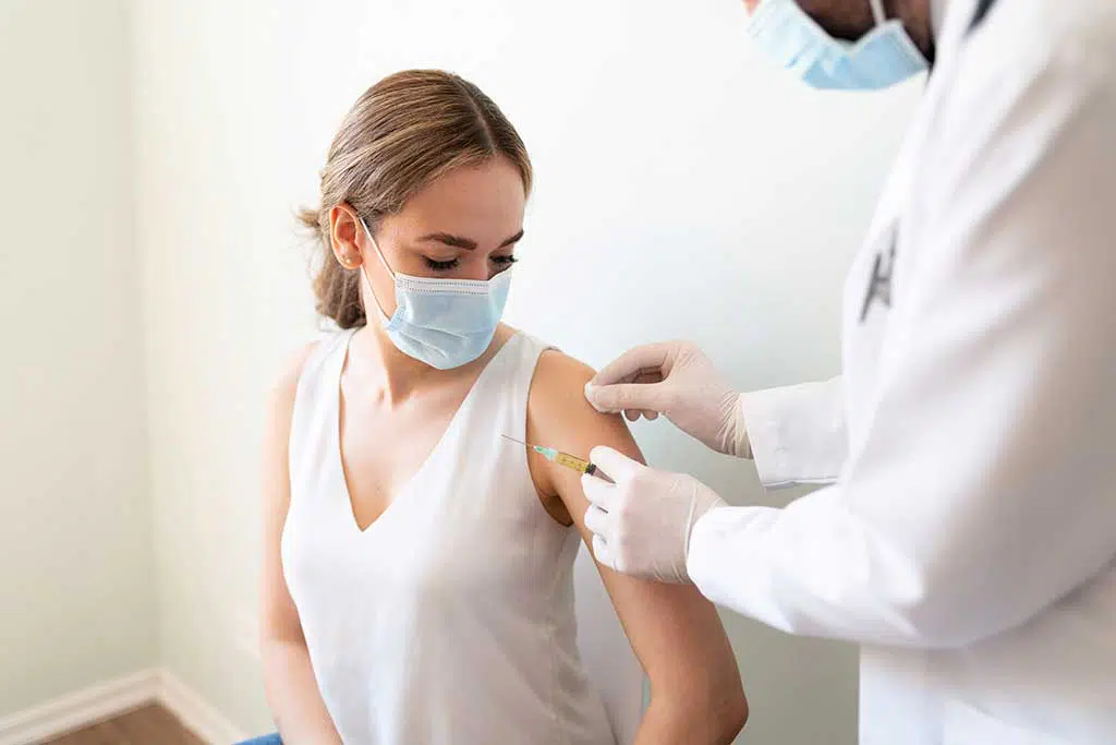 Photo of a woman having a bandage put on arm after vaccine